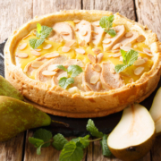 Birnentarte French pear tart with custard, almonds and mint close-up on a sl